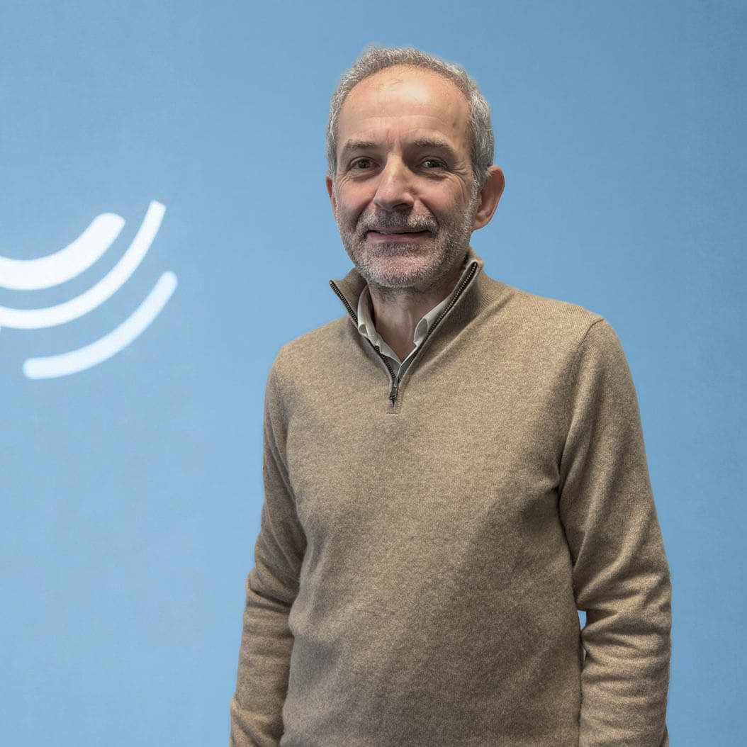 Portrait professionnel d’un biologiste médical souriant devant un fond bleu avec logo stylisé de laboratoire.
